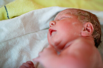 Newborn child crying seconds and minutes after birth. Cute tiny new born baby girl on towel. New...