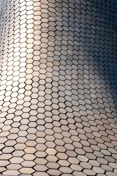 Hexagonal metal facade with repetitive patterns and reflective textures, modern architecture and urban design, ideal for design, construction and background visuals.