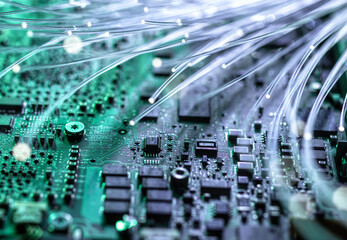 Close-up of a circuit board with glowing fibre optics representing data and innovation