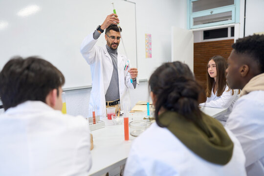 Chemistry teacher making experiment with students in laboratory classroom at school