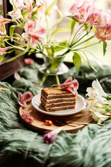 A honey cake (medovik) with natural ingredients rests beside fresh flowers, creating a cozy and aesthetic food presentation
