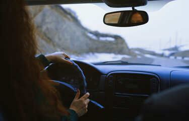 Redhead woman driving on a snowy mountain road during a road trip