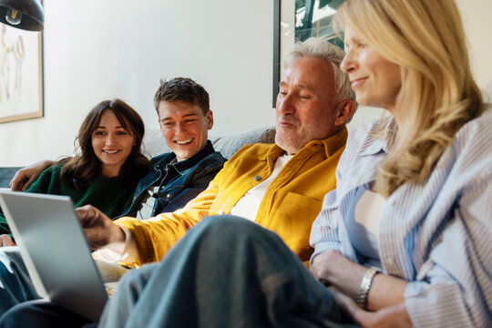Family enjoying time together on the sofa with a laptop at home