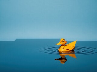  A delicate origami duck floats serenely on a tranquil pond. origami