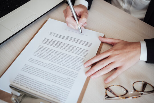 Businesswoman signing documents with pen at office
