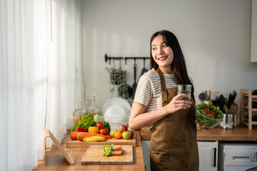 Asian woman eatting healthy salad and drink water in kitchen at home. 