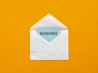 White envelope containing light blue remember note on orange background