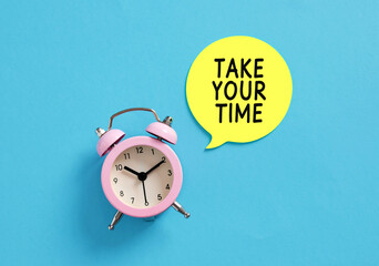 Pink alarm clock with take your time message suggesting slow living