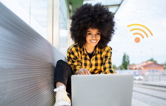 Woman using laptop on bench with digitally generated WIFi logo