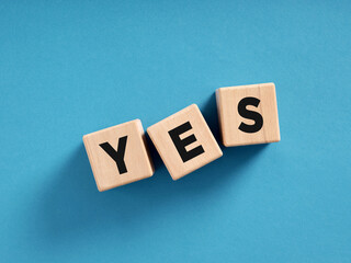Wooden cubes spelling yes on blue background