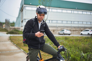 Man checking phone while stopped on electric bike in industrial area