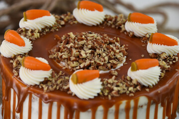 Carrot Cake with Cream Cheese Frosting and Drizzle caramel chocolate sauce with crushed nuts isolated on napkin closeup view of classic delicious cake
