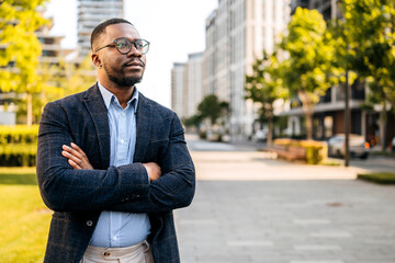 Businessman confidently poses in urban park during afternoon in a modern city landscape
