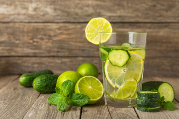 Cucumber water with lemon, lime and mint on a wooden table. Water infused with sliced...