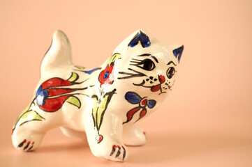 A cat figurine with a pattern on a pink background.