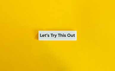 Let’s Try This Out Phrase on Letter Tile on Yellow Background. Minimalist Motivation and Experimentation Concept.