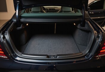 Luxury sedan trunk open, revealing a spacious carpeted interior in a studio setting