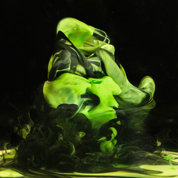 Bright green liquid ink forms dynamic tornados in water against a black background