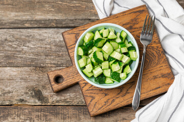 Cucumber on wooden background. Slice of cucumber on background. Fresh organic green cucumbers gherkin. Vegan. Salad ingredient. Farm vegetables. Cut vegetables with knife. Space for text. Copy space