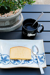 Hot Americano in Black Ceramic Cup with Butter Cake on Wooden Table