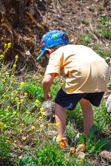 Fototapeta premium Boy touching turtle or tortoise in nature. Toddler and turtle. Children's love or awareness of nature. Model, people, human. Kid. Animal. Vertical photo.