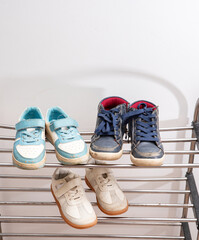 Dirty children's shoes stand on the shelf. Decluttering and cleaning