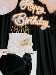 Elegant birthday cake celebration with golden accents and a queen theme in a stylish setting