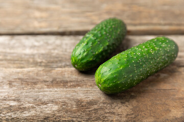 Cucumber on wooden background. Slice of cucumber on background. Fresh organic green cucumbers gherkin. Vegan. Salad ingredient. Farm vegetables. Cut vegetables with knife. Space for text. Copy space