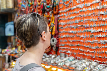 Tourist admiring handcrafted jewelry displayed on a stall in a traditional souk, exploring local crafts and culture