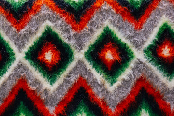 A colorful fabric presents a repeating geometric design with vibrant patterns and textures, rich colors, and depth. Ukrainian textile. Woolen carpet.