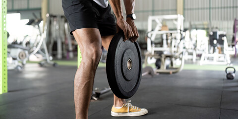 Weightlifting: Young Man Lifting Heavy Plate in Gym
