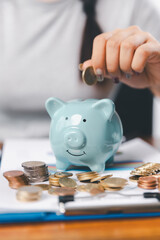 Businesswoman saving money with piggy bank and coins on desk, financial planning and investment...