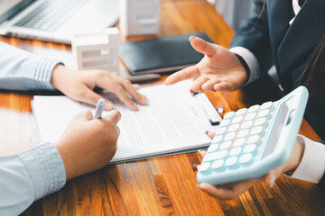 Home loan officer uses calculator with house plan loan real estate or property. important to loan calculator seek real estate, finance insurance advice ensure smart financial decisions for business.