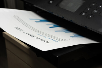 Closeup of printed business document emerging from office printer, concept of financial reporting...