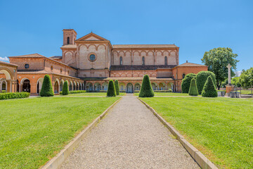 Saint Christopher Church of the Charterhouse of Ferrara, featuring a beautiful cloister and lush lawn, stands as a significant monument in the city on a sunny day under a clear blue sky