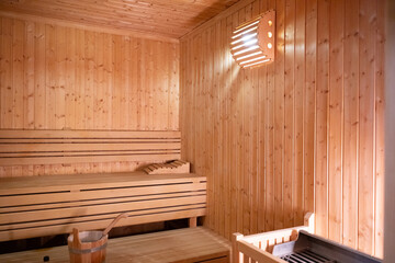 Empty Wooden Sauna Interior.Wide view of a warm and empty wooden sauna with rolled towels and...