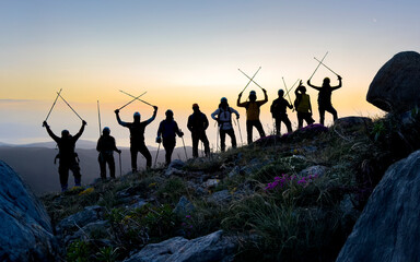silhouette of a large group of climbers posing for a souvenir pose at the summit