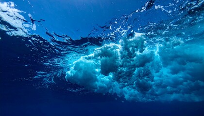 The underwater perspective showcases a wave's powerful form, captured in shades of blue. The water's movement is visible with churning foam.