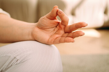 Close up of woman sitting cross-legged, practicing yoga and enjoying meditation.Woman keeping hands...