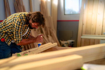 Carpenter carefully applying glue to wooden plank, preparing to assemble furniture or other...