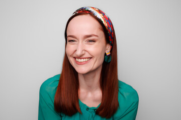 Cheerful woman in colorful headband isolated on grey