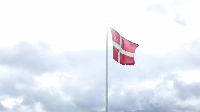 Denmark flag waving in the wind with a background of grey moody sky