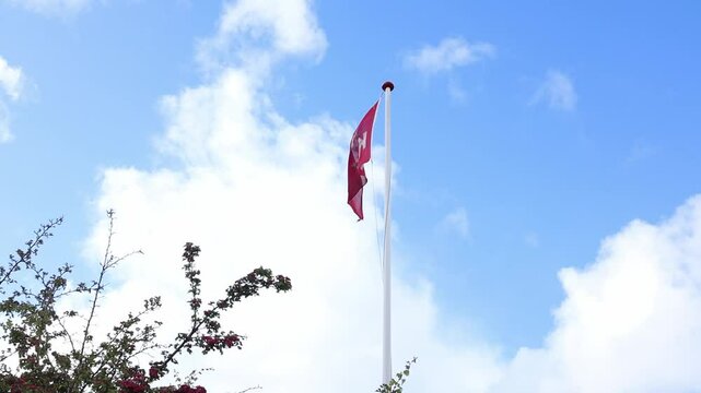 Danish flag with letters waving in the wind with a background of a blue sky with clouds