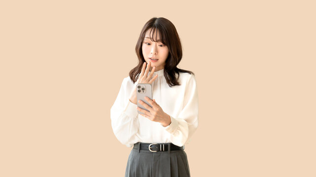 スマホを見てショック・驚く女性・ビジネスウーマン・会社員
