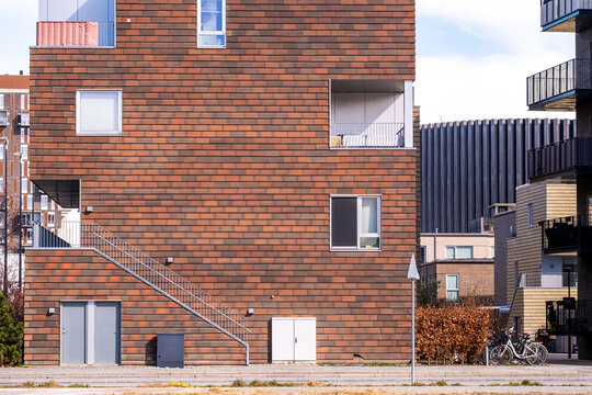 Modern residential facade in &Oslash;restad, Copenhagen with brick texture, balconies, and geometric design, ideal for real estate, architecture, and urban development stock.