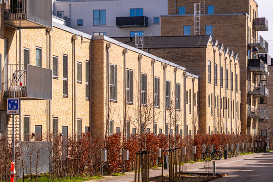 Row of residential houses in &Oslash;restad, Copenhagen with brick facades, trees, and pedestrian street, showcasing urban planning, lifestyle, and contemporary architecture.