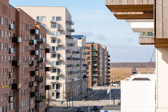 Modern residential district in Ørestad, Copenhagen with brick facades, balconies, trees, and clear sky, ideal for architecture, real estate, and urban design stock imagery.