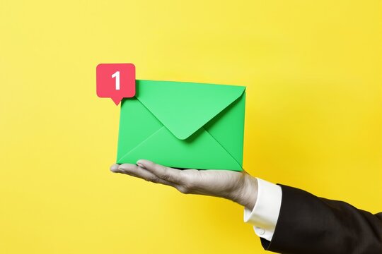 Green mail envelope with notification icon held by human hand in suit on vibrant yellow background, creative concept of email alert. Ai generative