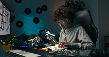 Carefully holding the tool, the boy solders wires onto a circuit board. He gains confidence while learning basic electronics and practical engineering skills.