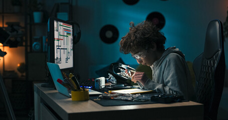 Wearing safety glasses, the child fixes circuit paths under magnification. He practices soldering...
